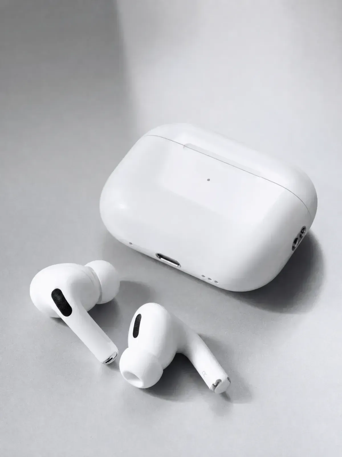 White wireless earbuds and their charging case photographed as a clear source product.