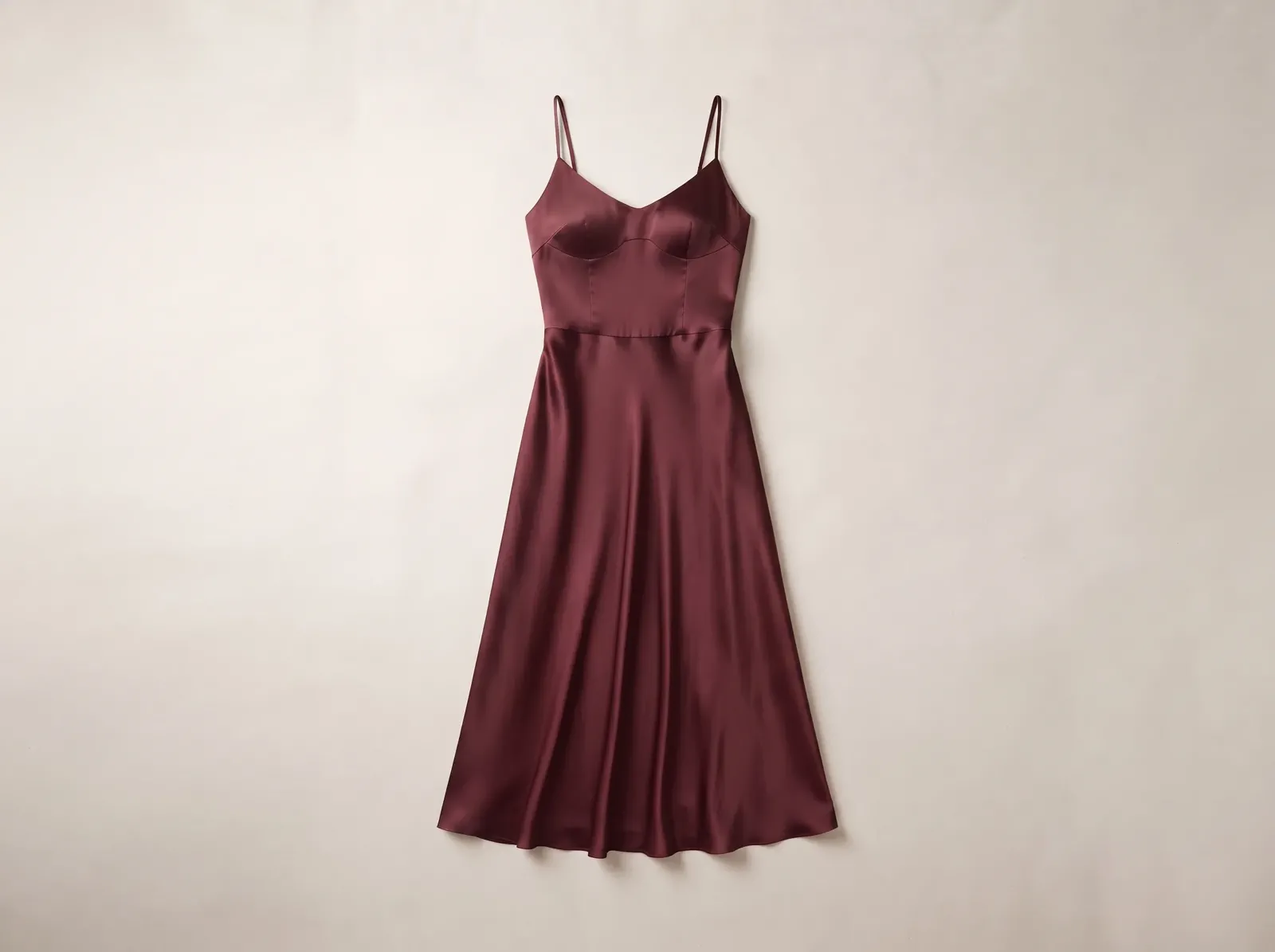 A women’s satin midi dress shown in full with its straps, neckline, waist shaping, drape, and hem readable.