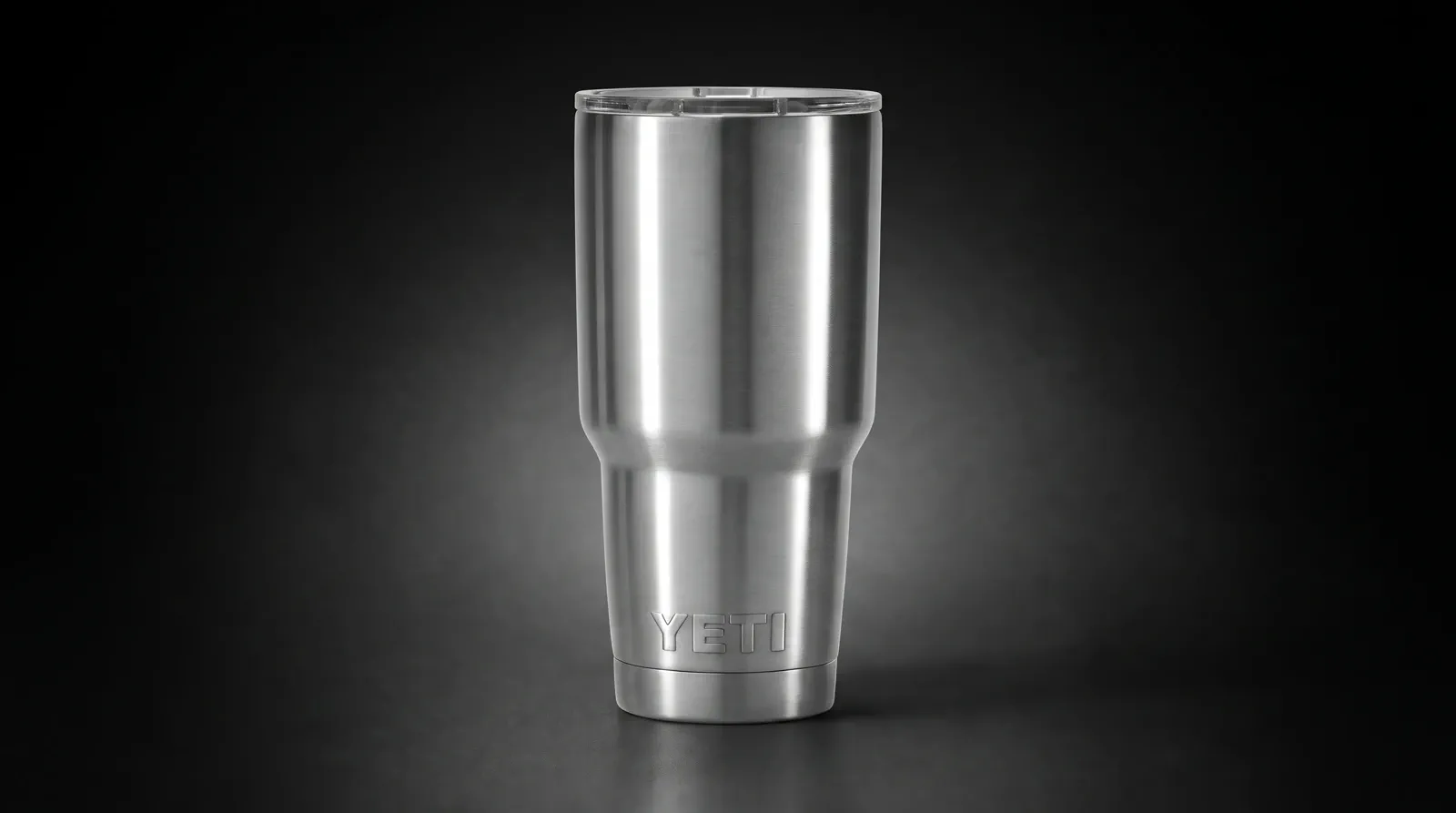 A reflective stainless tumbler defined by controlled strip highlights on a dark field.