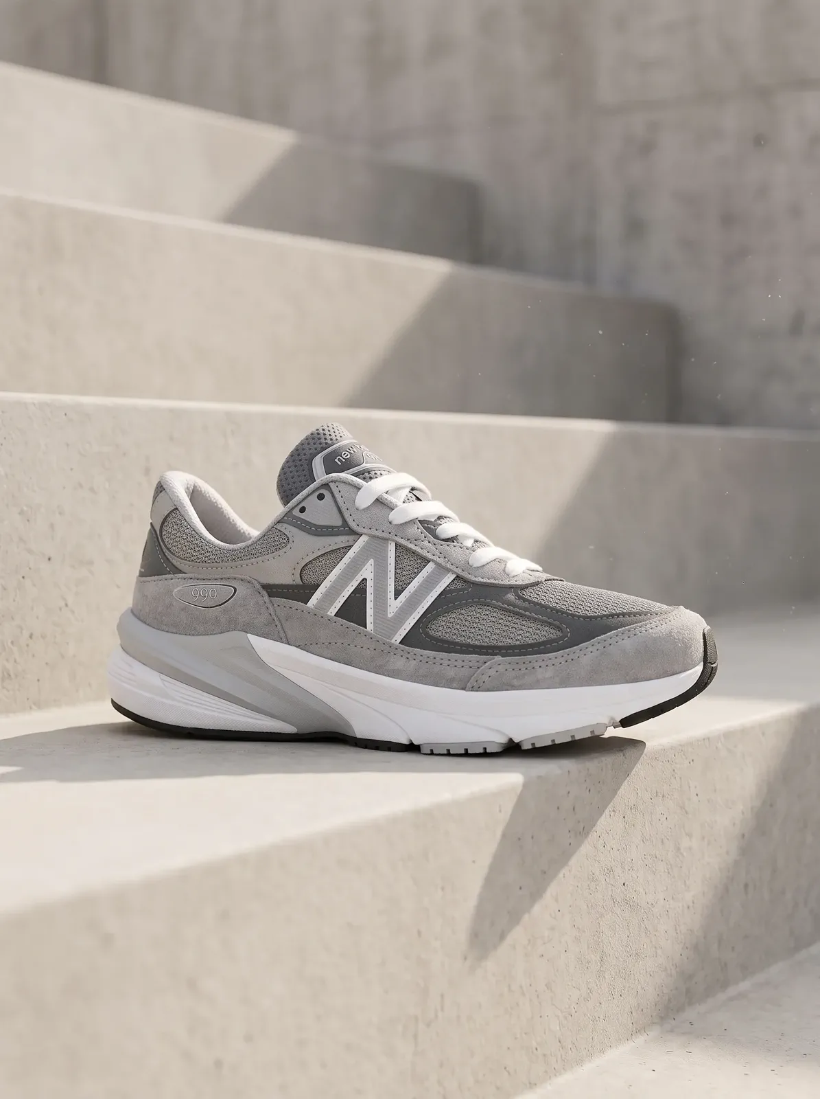 A gray layered performance shoe placed on architectural steps while its mesh, overlays, and sole remain readable.